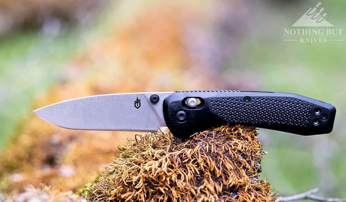 The Gerber Sedulo folding knife outdoors on a mossy tree. 