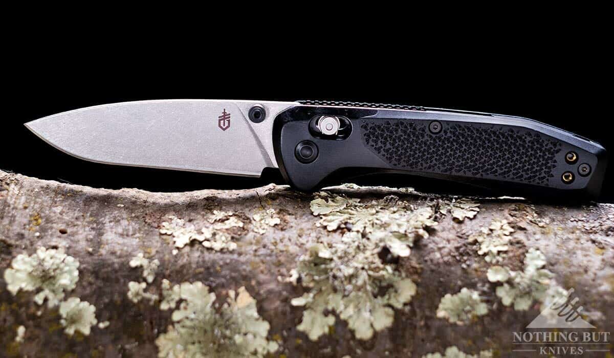 The Gerber Sedulo pocket knife is part of Gerber's Reserve collection. It is pictured here on a tree branch in front of a dark background.