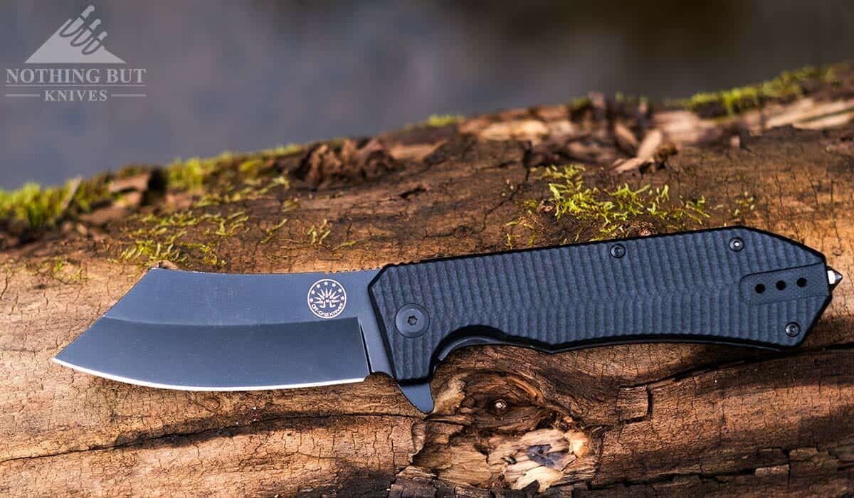 The Off-Grid Sea Dog folding knife on the edge of a creek with the blade open. 