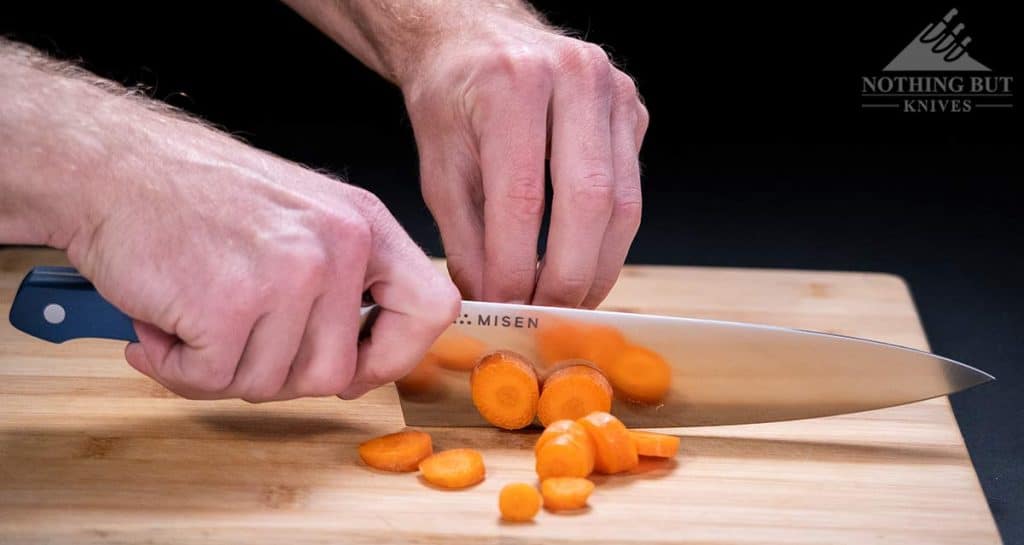 A close-up of the Misen chef knife dicing a carrot on a cutting board. 