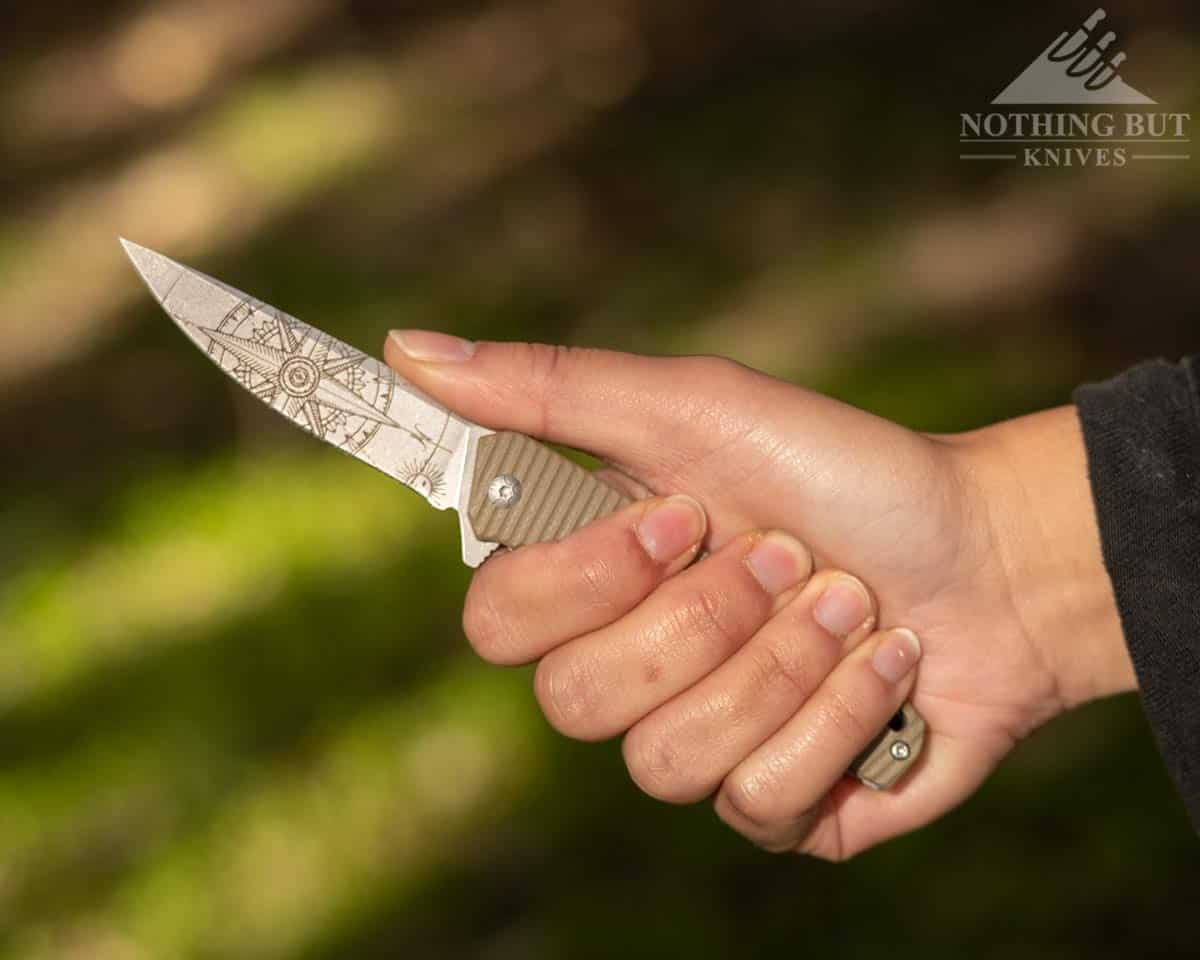 A close-up of a woman's hand holding the 3V Gear React knife with a Filipino grip. 