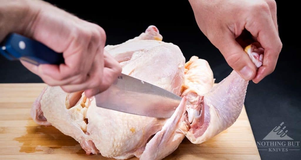 A close-up of a drumbstick being removed from a chicken with the Misen 8 inch chef knife.