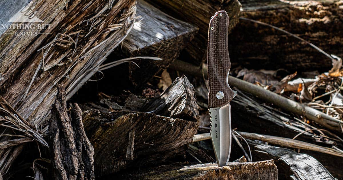 The Buck Sprint Pro With burlap Micarta handles on a wood pile.