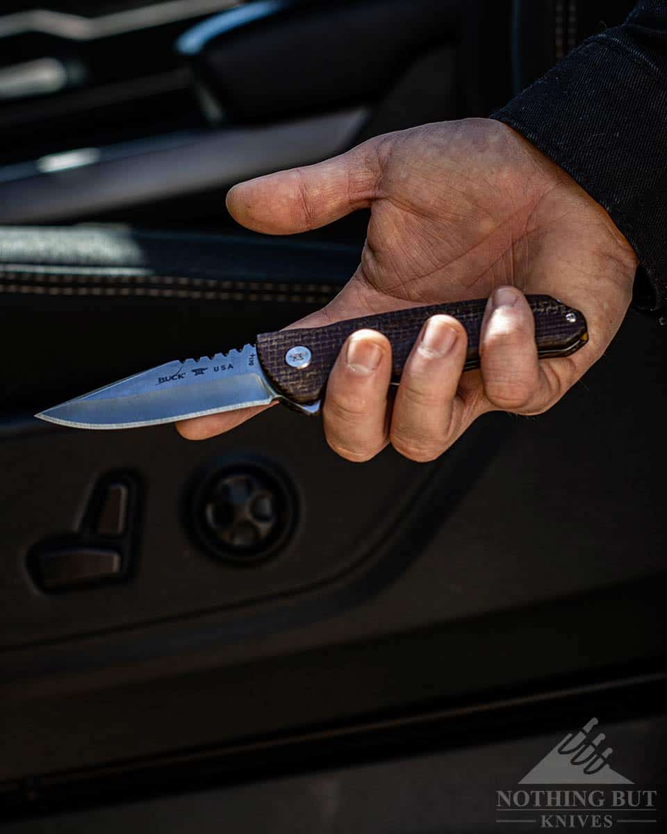 The Buck Sprint Pro in a man's hand next to a car. 