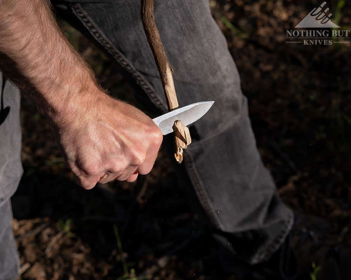 A man sharpening a stick with the Civivi Elementum Damascus knife.