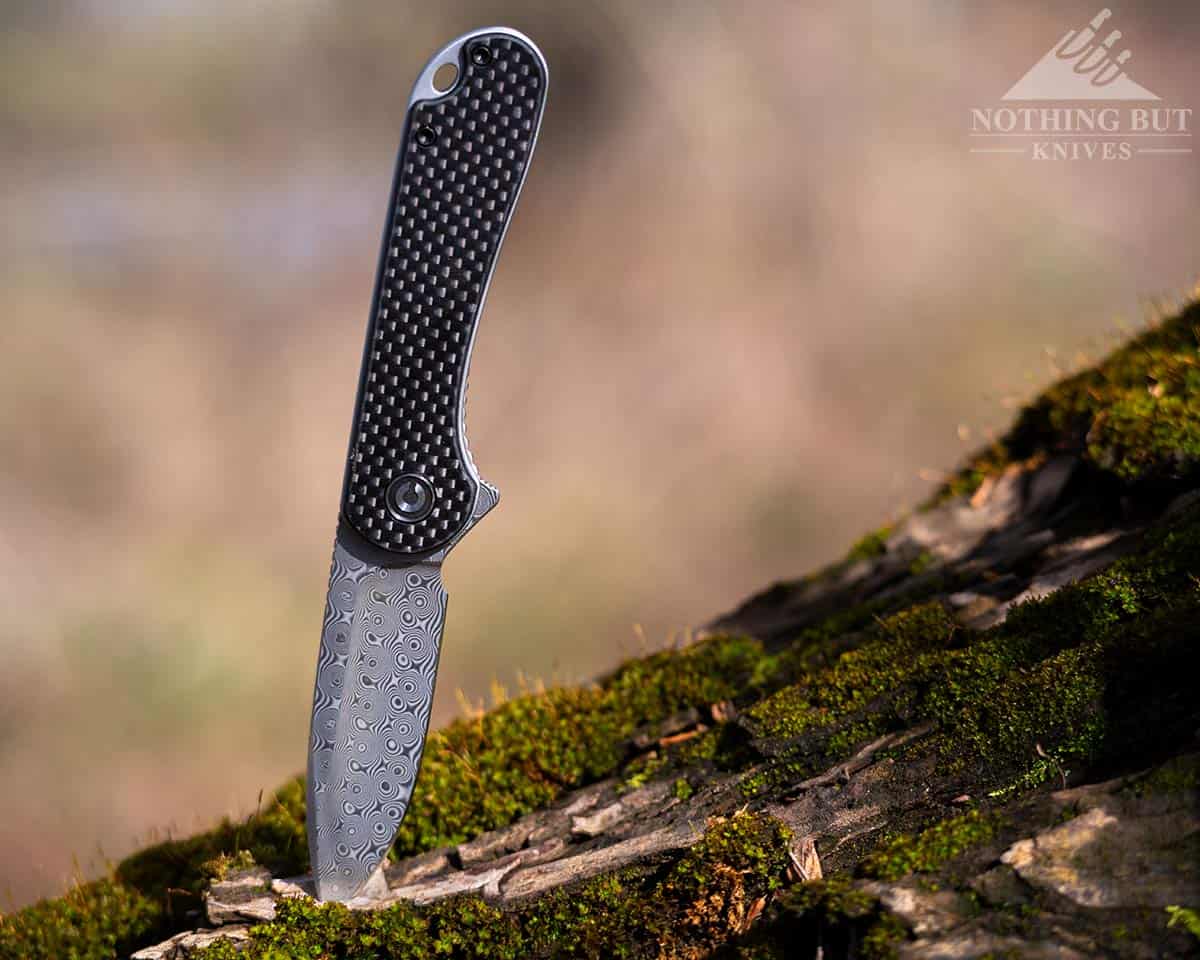 The Civivi Elementum Damascus steel folding knife in the open position outdoors. 