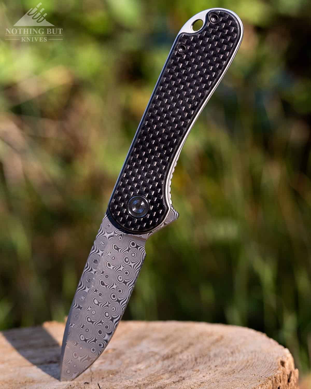 The Civivi Elementum folding knifeing sticking in a stump with the handle up. 