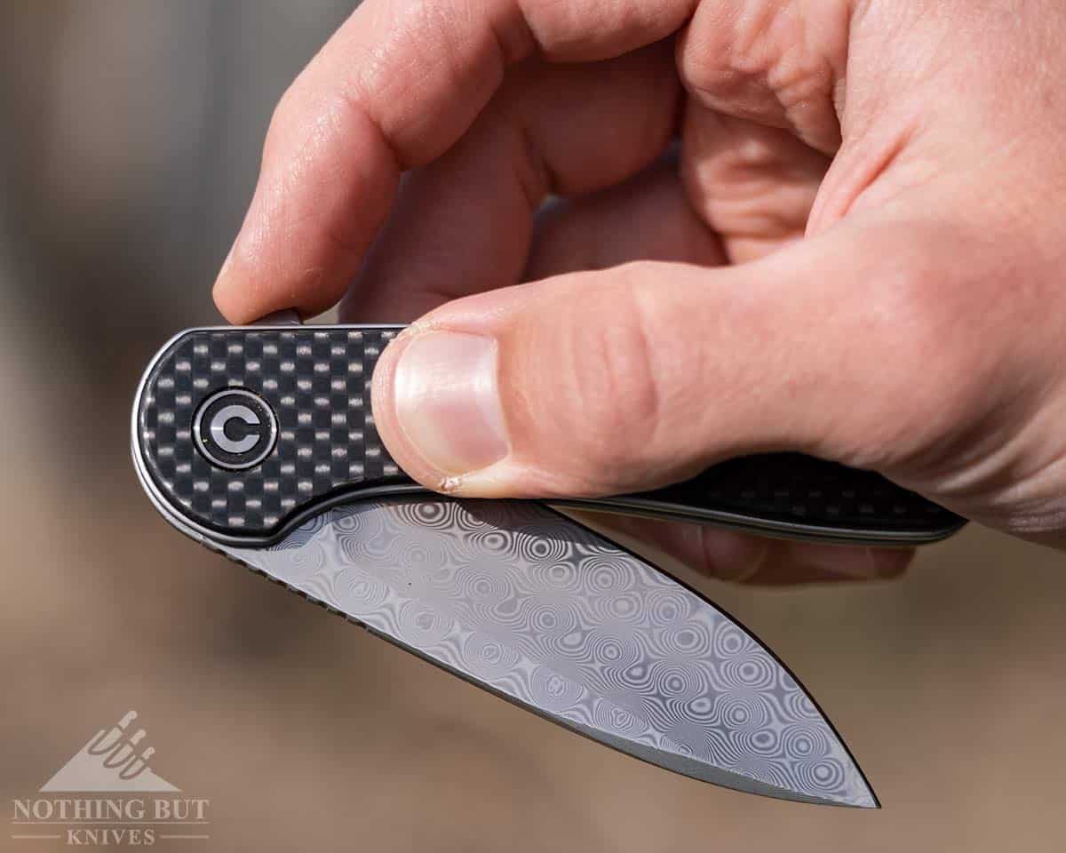 A man's hand opening the Civivi Elementum Damascus folding knife. 