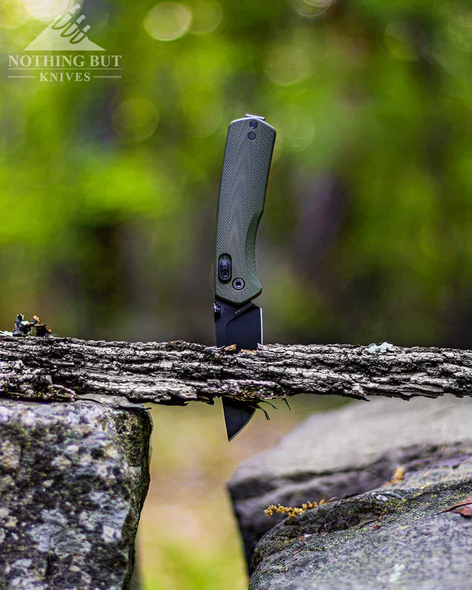 Vertical oriented image showing The James Brand Carter knife sticking through an old weathered piece of wood. 