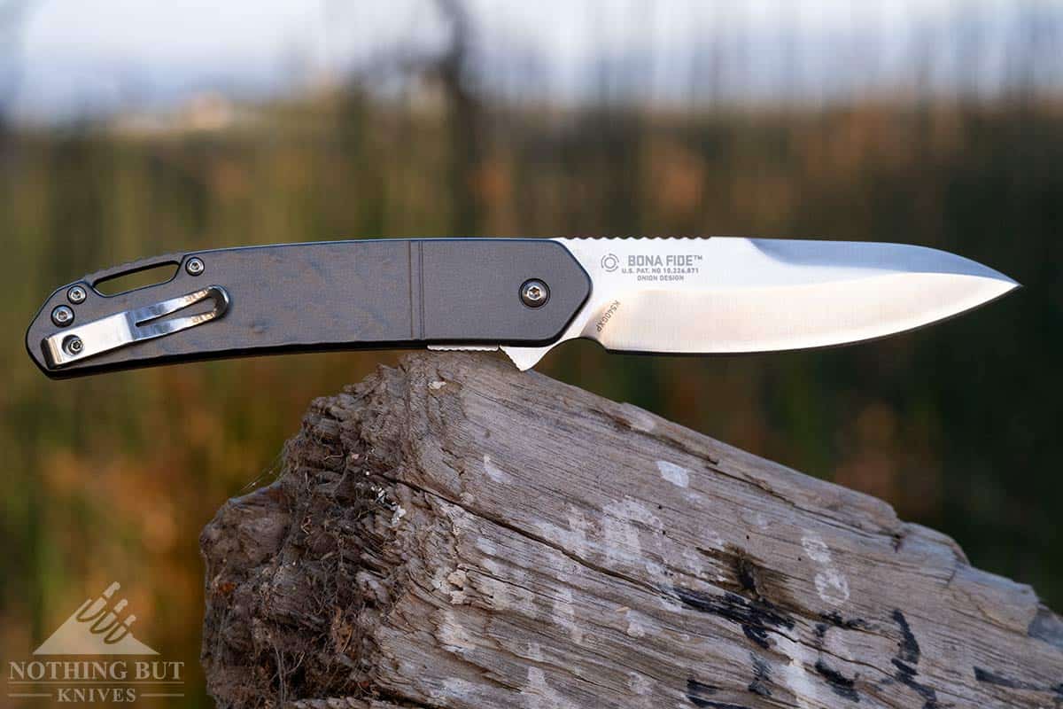The Bona Fide Pocket knife with a D2 steel blade on a tree stump outdoors. 