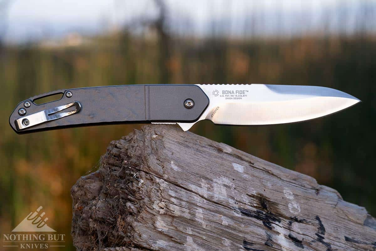 Crkt Bona Fide Review - Image 7 The Bona Fide Pocket knife with a D2 steel blade on a tree stump outdoors.