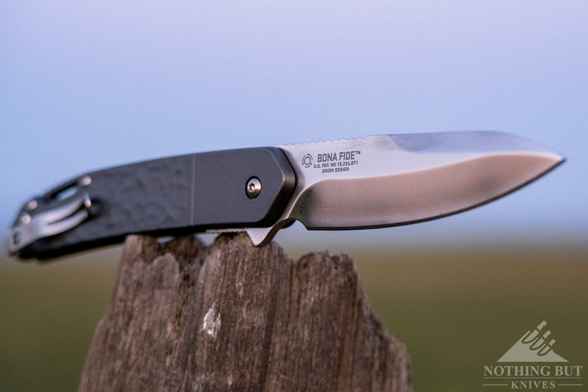 Crkt Bona Fide Review - Image 14 The Silver Bona Fide is a Ken Onion design shown here on a fence post outdoors.