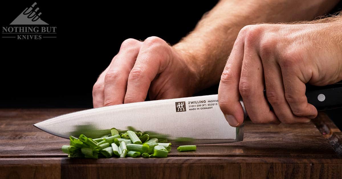 Zwilling 8 Inch Professional S Chef Knife Review - Image 6 The Professional S Chef knife chopping green onions on a wood cutting board.