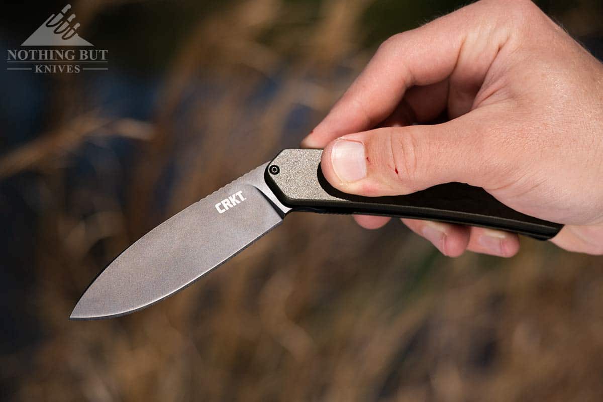 A close-up of a man's hand opening the CRKT Bona Fide pocket knife. 