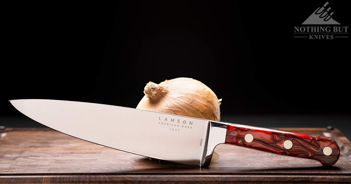 The Lamson Premier Fire 8 inch chef knife on an end grain cutting board in front of a dark background. 