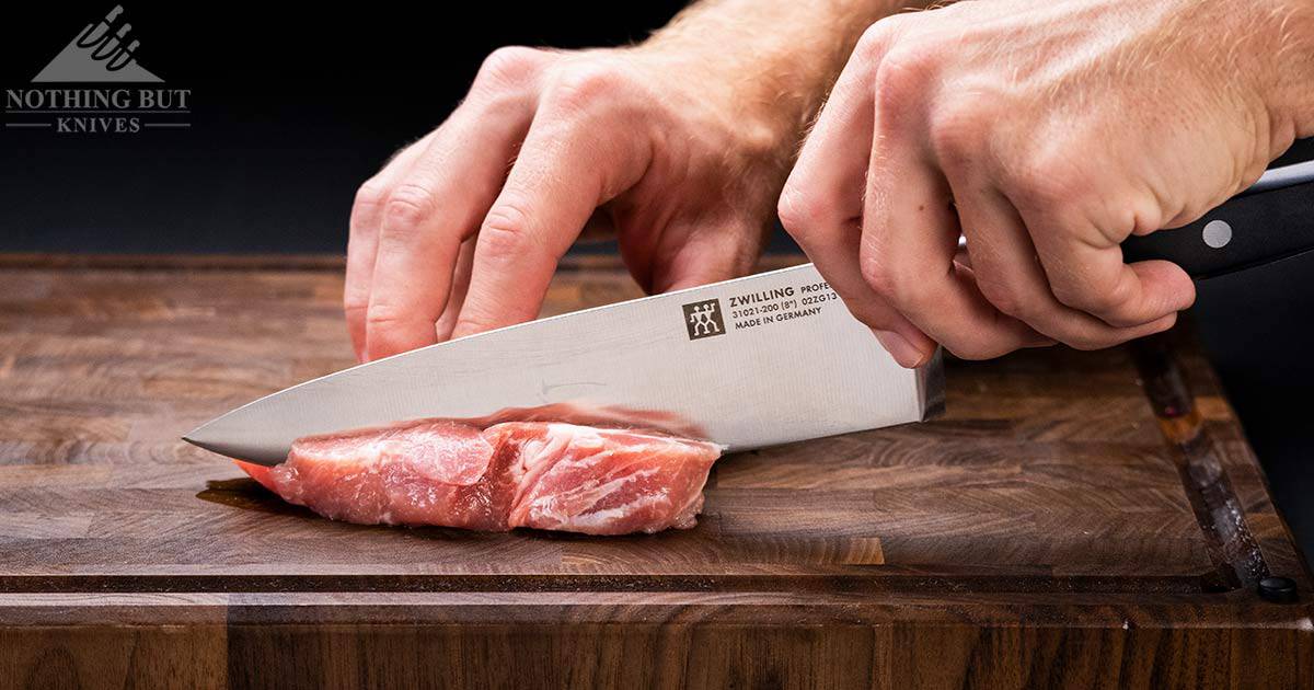 A close-up of the Professional S chef knife cutting through raw pork. 