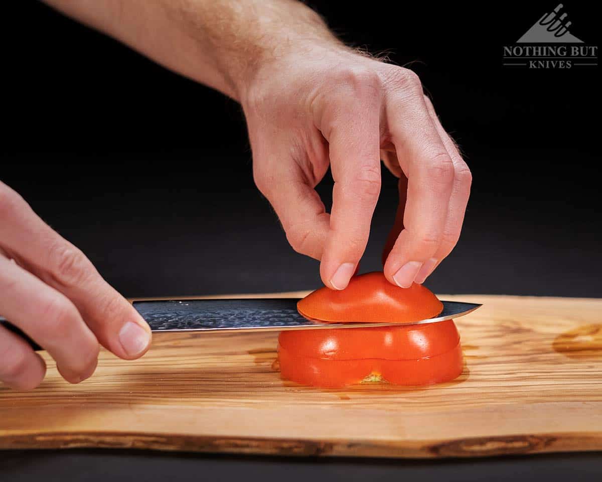 A close-up of the Enso HD santoku knife slicing through a tomato.