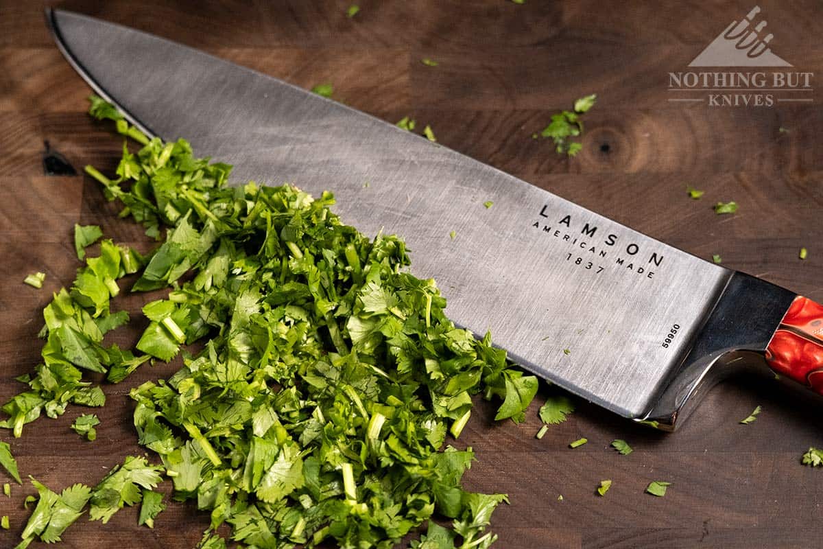 The Lamson 8 inch chef knife next to a pile of chopped herbs on a cutting board. 