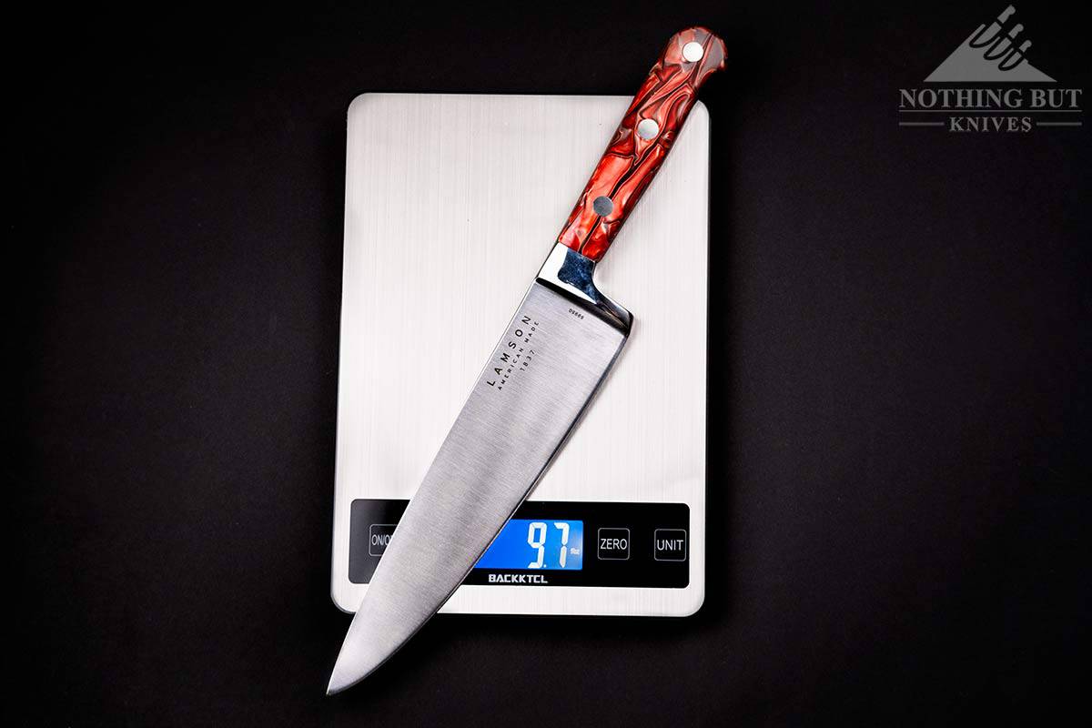 Lamson 8 Inch Premier Forged Chef Knife Review - Image 1 The 8 inch Lamson Fire Forged Premier chef knife on a digital scale over a dark background.