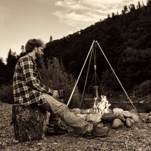 Kitchen and outdoor knife reviewer, Andrew North sitting by a campfire. 