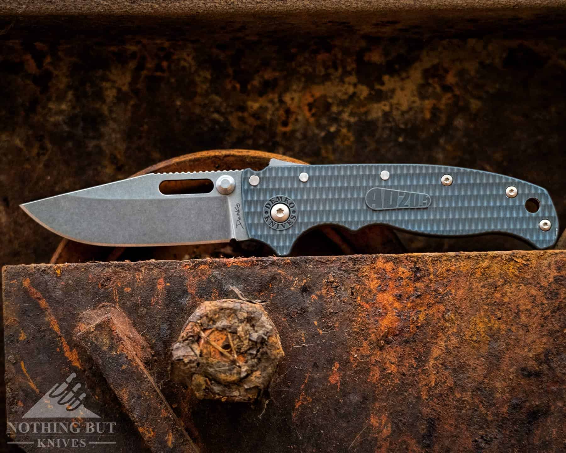 Header image for our in-depth review of the Demko 20.5 pocket knife featuring the knife in the open position on a runty steel I beam.