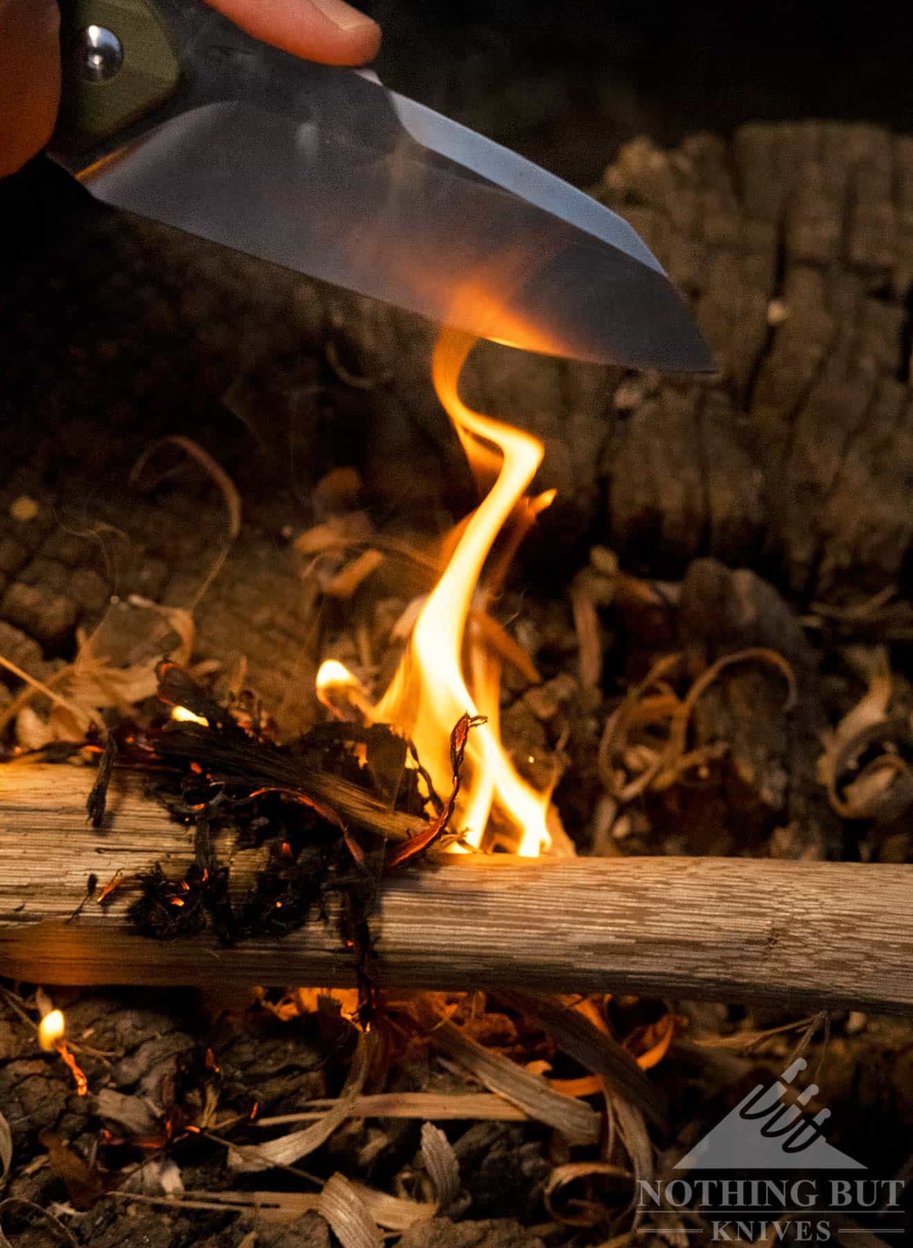 A close-up of a small camp fire started with the Kepler fixed blade knife.