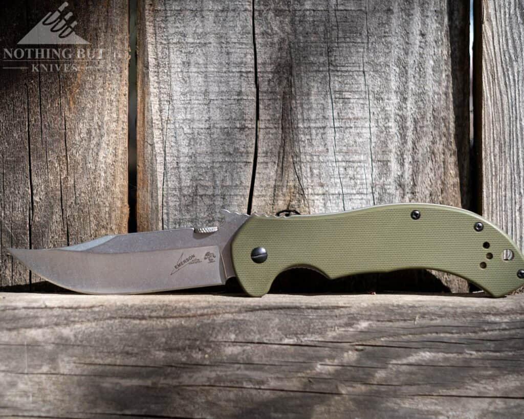 The Kershaw Emerson CQC 10K pocket knife on a wood fence in the open position. 