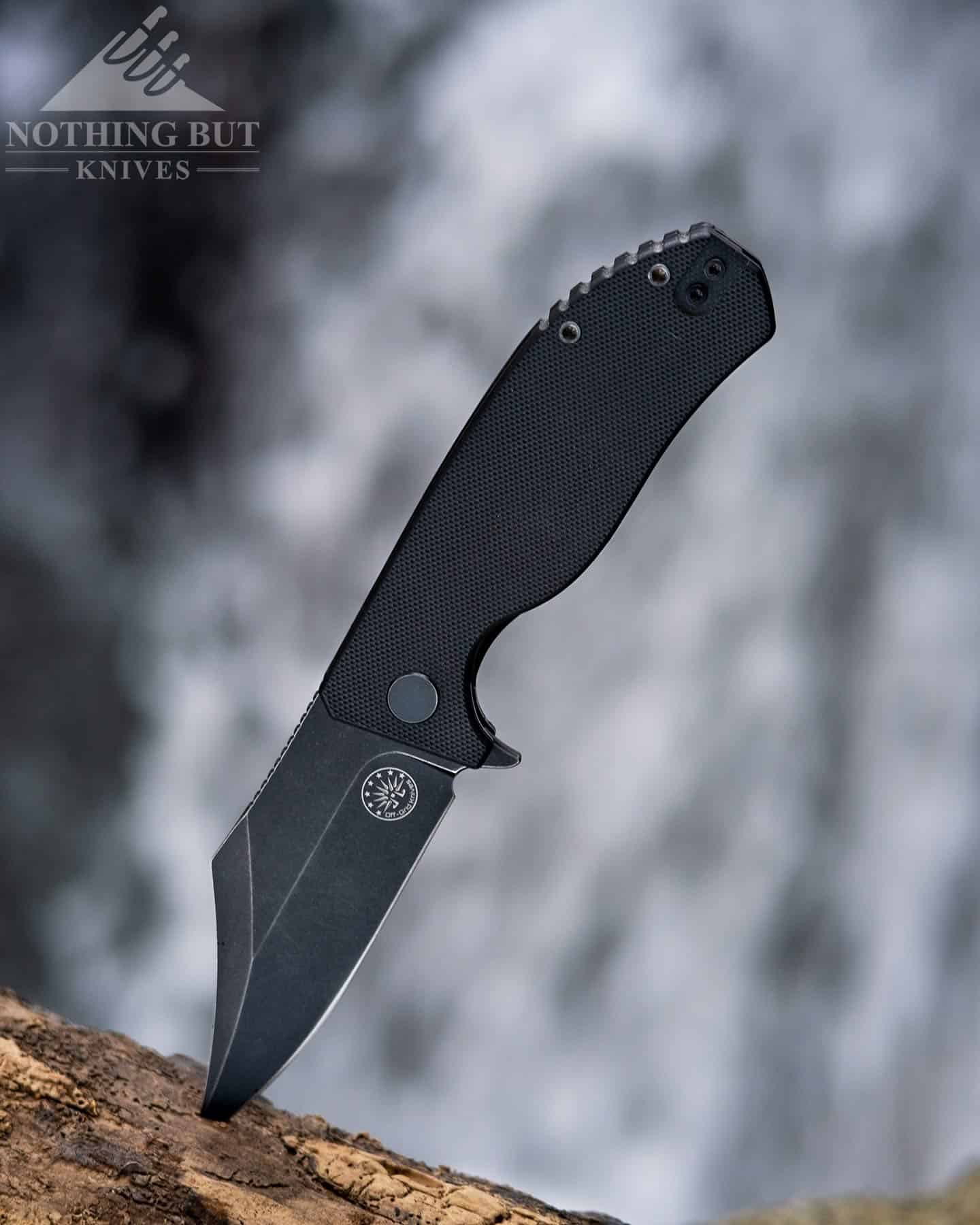 Header image for our in-depth review of the Off-Grid Caiman pocket knife. Pictured here in fron of a mountain waterfall.
