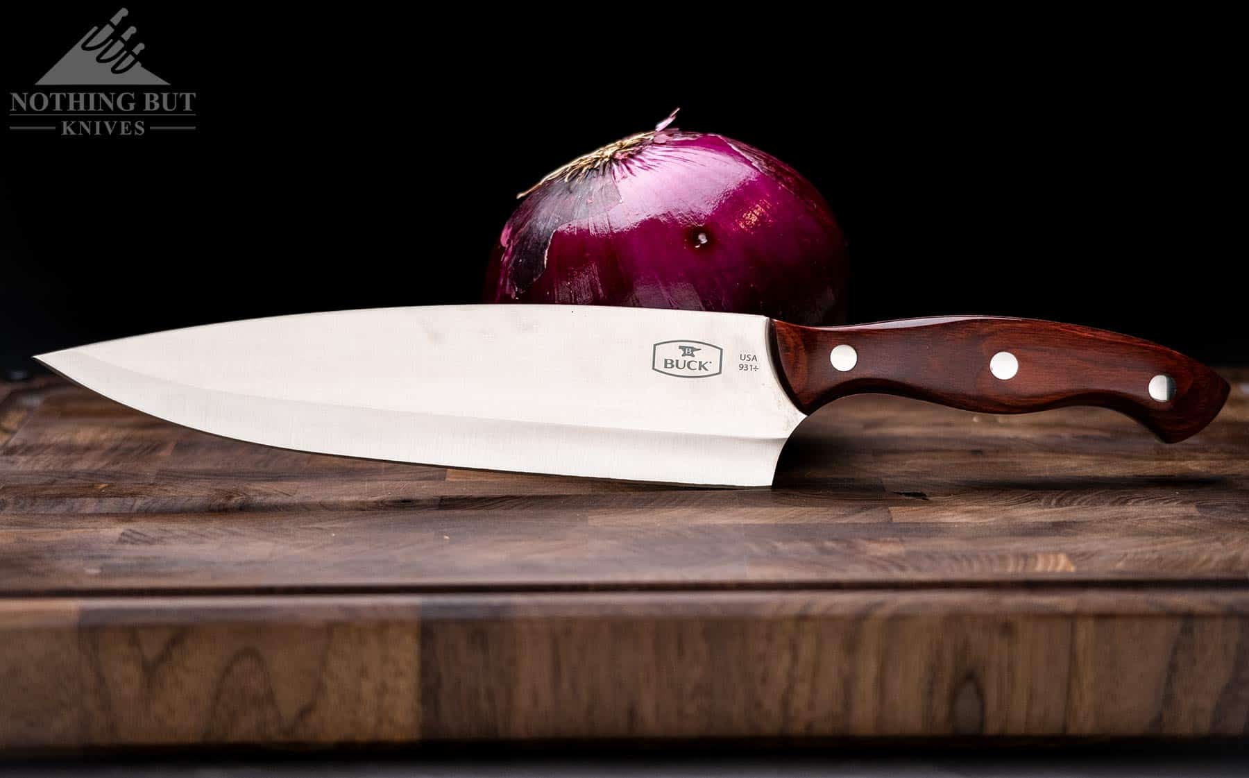 The Buck 931 chef knife is a similarly priced option to the Mattia Borrani chef knife. The Buck is shown here on a wood cutting board with a red onion. 