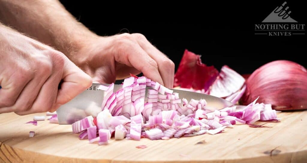 The Misen 8 inch chef knife dicing onions. This is the header image for the conclusion of our in-depth review. It shows this knife's capabilities in-spite of it's shortcomings. 