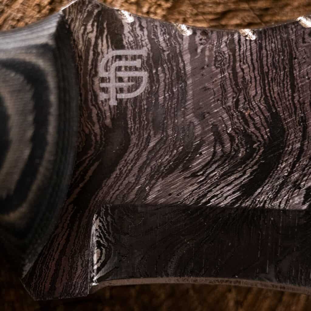 Forseti Steel Jim Baker Review - Image 2 A close-up image of a Forseti Steel knife blade that shows the logo that is engraved on the side.