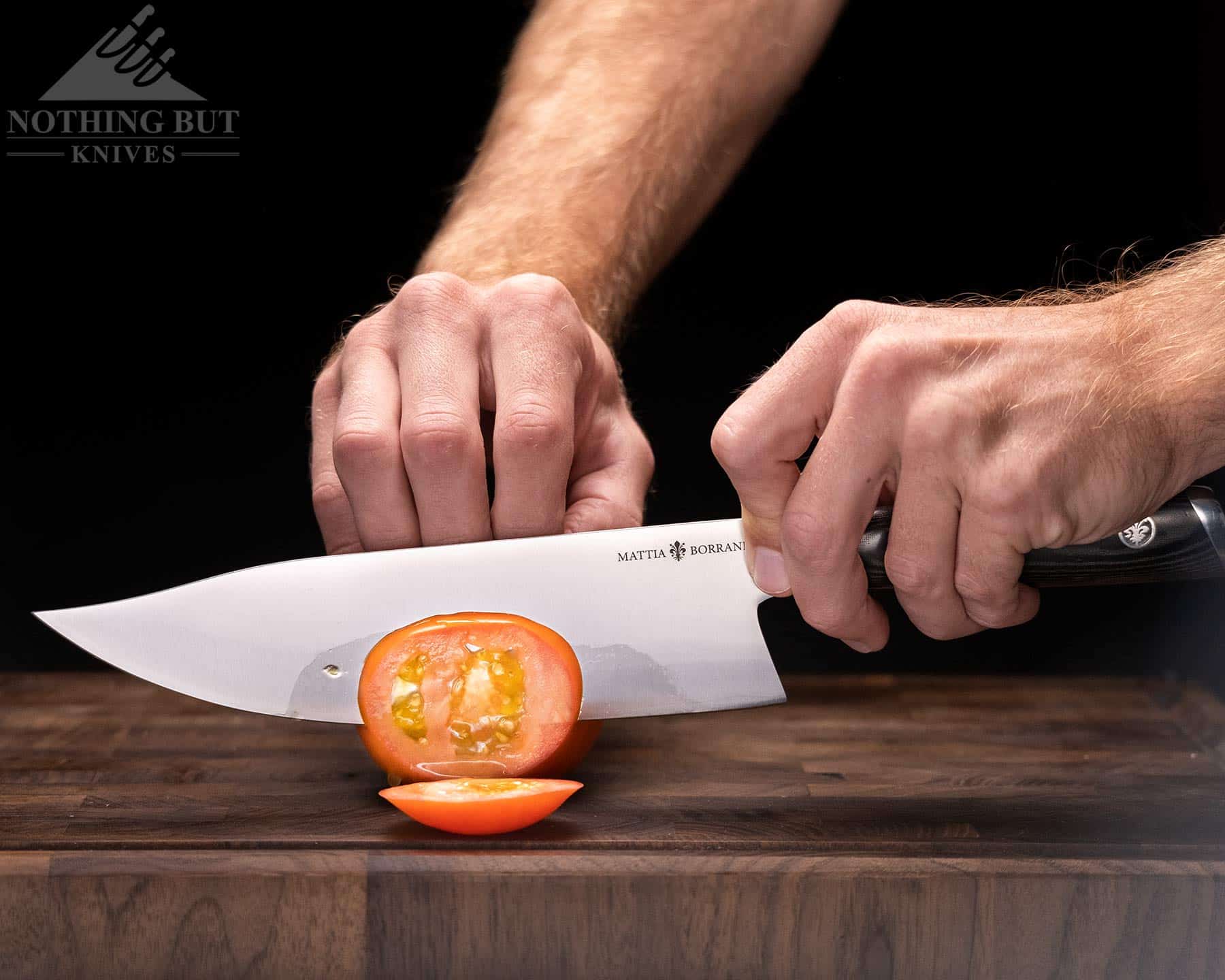 The Mattia Borrani Bowie chef knife slicing a tomato on an end grain cutting board.