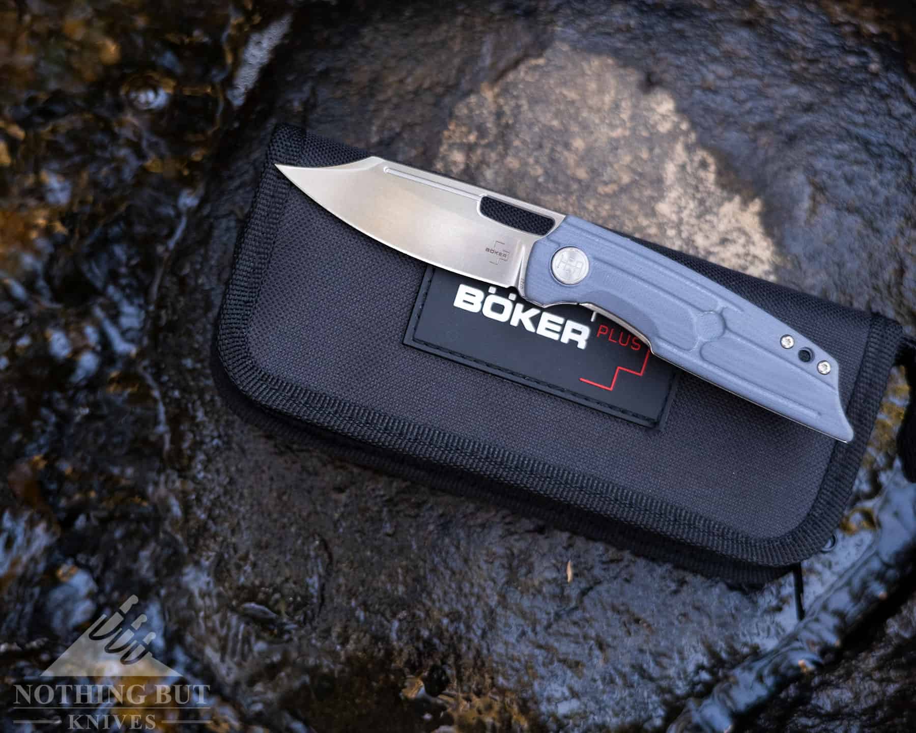 The Boker Plus HEA Hunter pocket knife in the open position on it's canvas carrying case outdoors. 