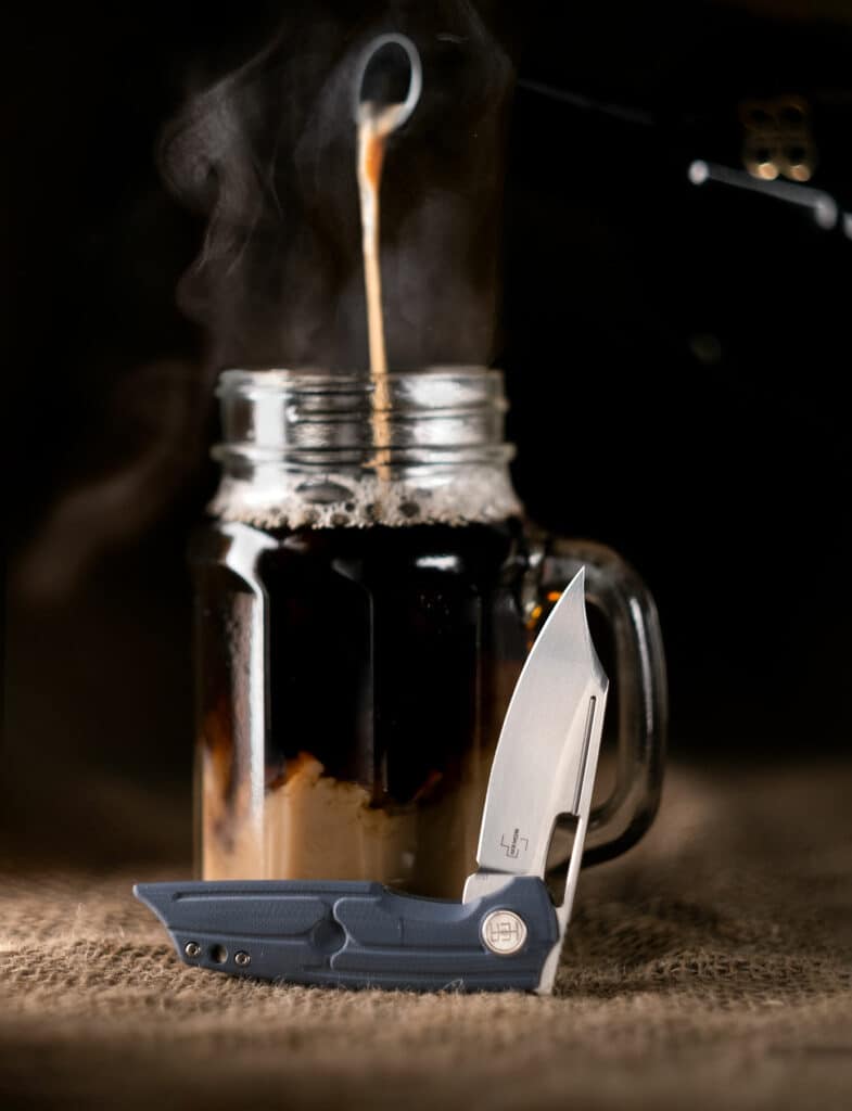 Boker Plus HEA Hunter Pocket knife in the half open position next to a glass of Irish Coffee. 