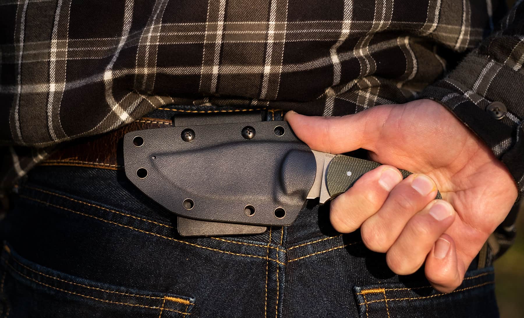 The Boker Plus Madman fixed blade knife set up for horizontal scout carry on a person's belt.
