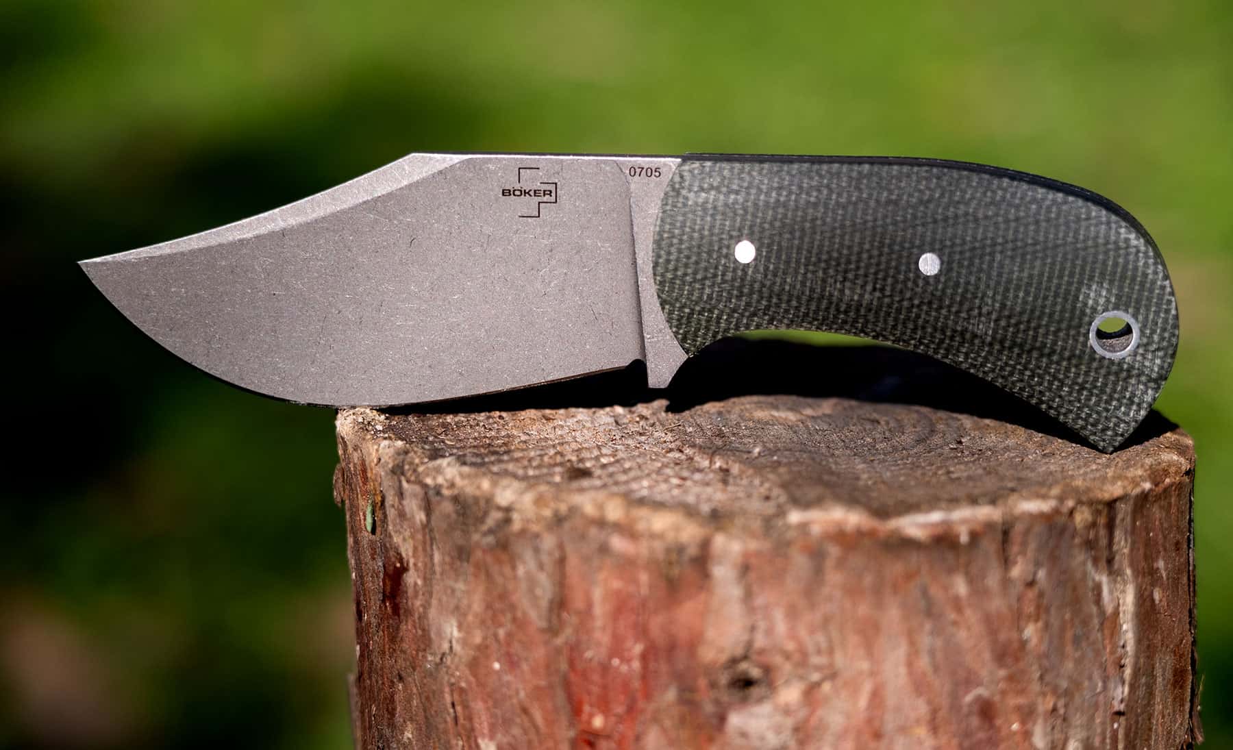 Boker Madman fixed blade knife outdoors on a piece of firewood to show the size and design.