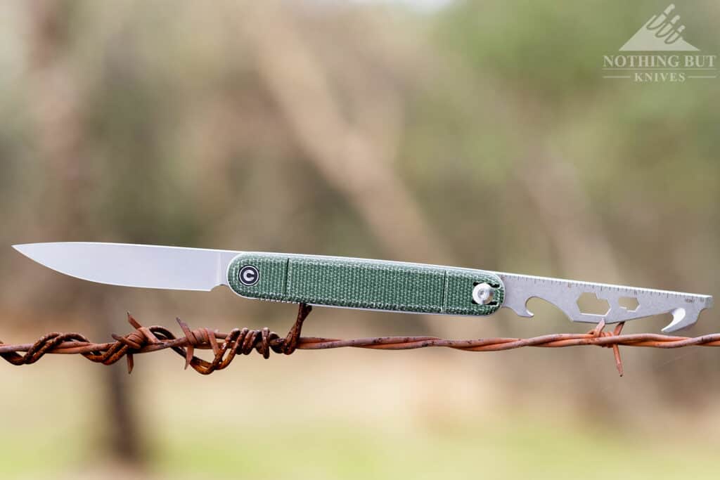 The Civivi Crit on a barbed wire fence with both blades open to show all the features of this pocket knife multitool hybrid.