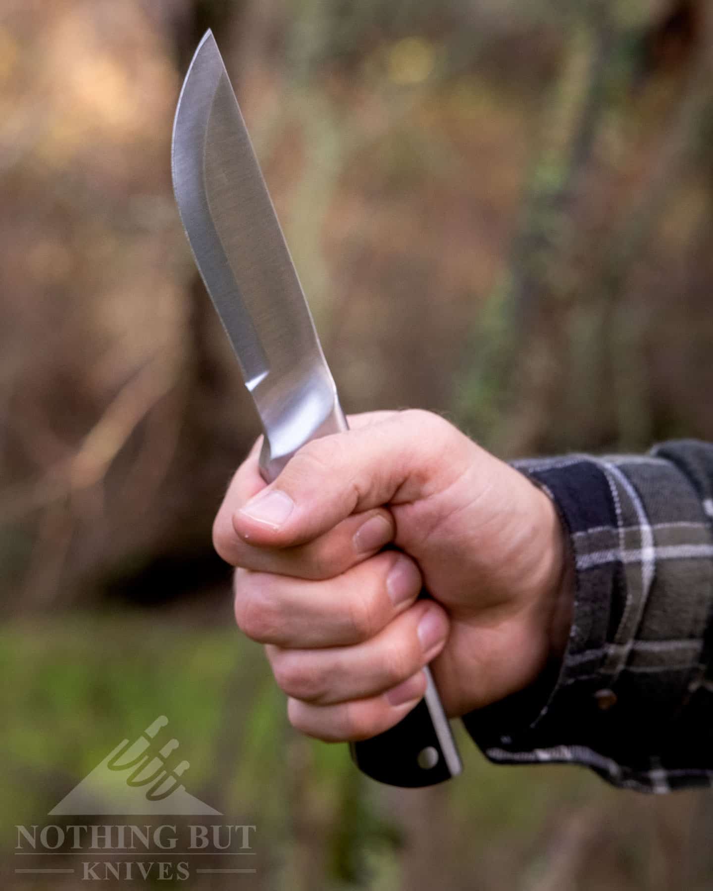 A close-up of the Maettiini Full Tang knife held in a gorilla grip. 