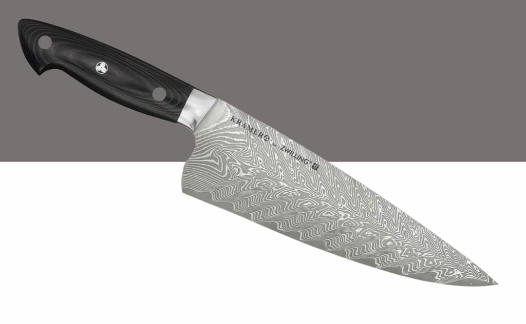 Zwilling By Kramer Damascus chef knife on a white and gray background. 