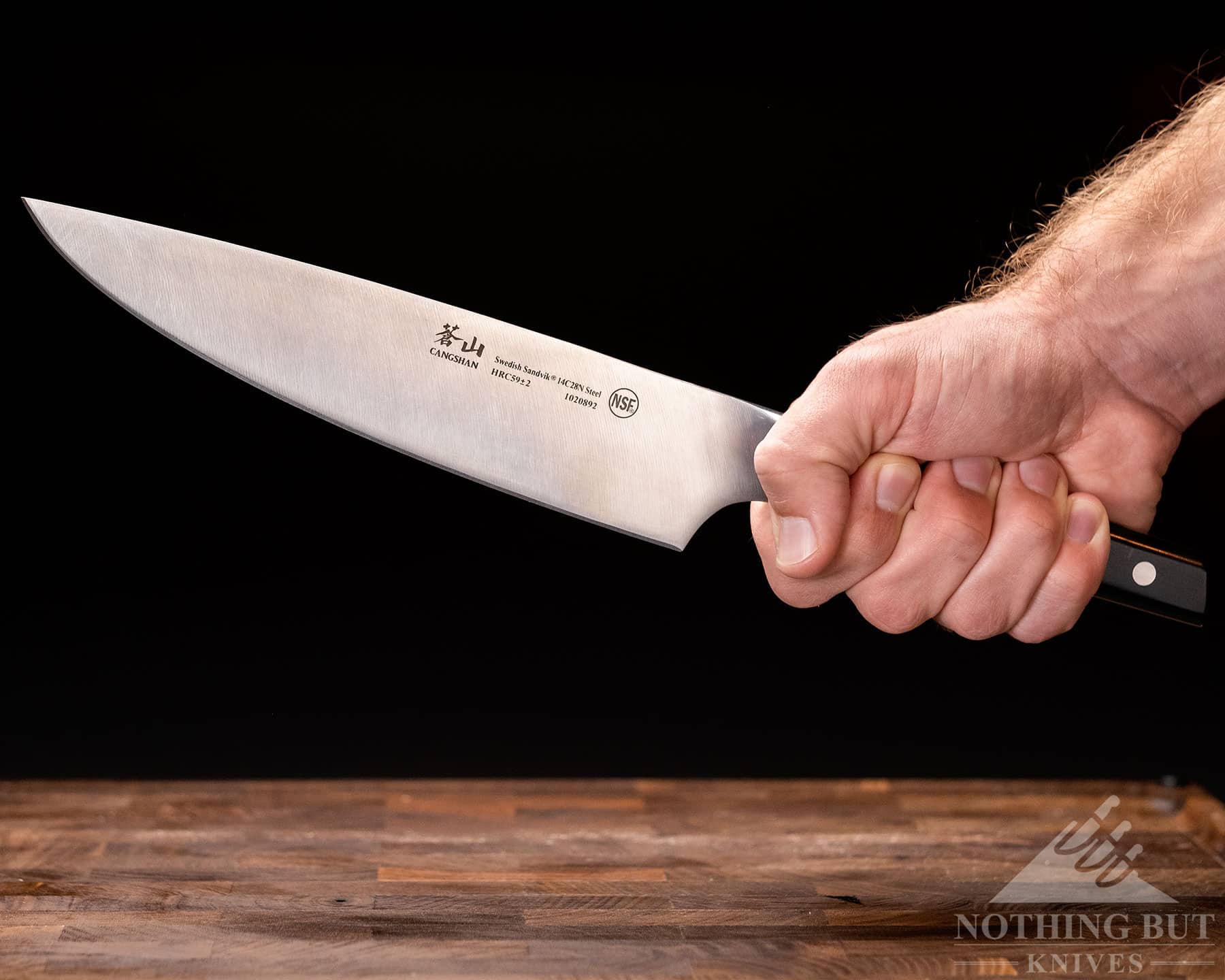 A person's hand gripping the Cangshan TC chef knife to show scale and the ergonomics of the handle. 