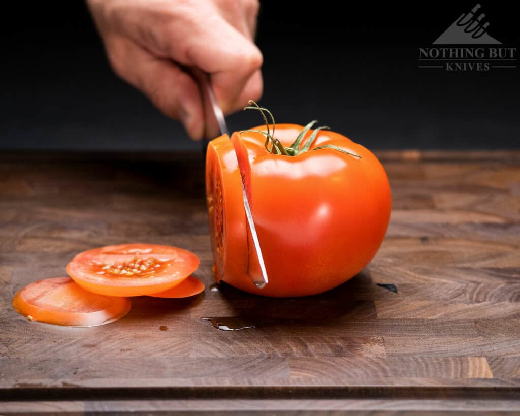 Close-up image of the tip of the Cangshan TC chef knife blade as it slices through a tomato.