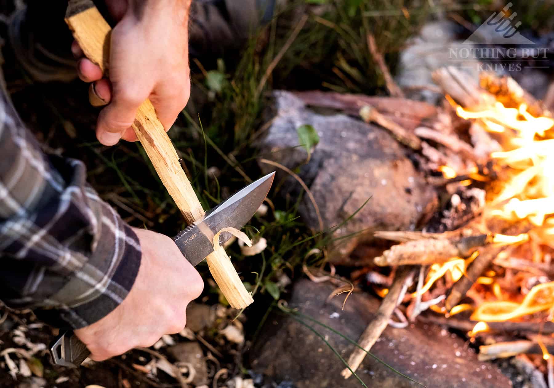 The Rock 62 fixed blade knife being used to carve next to a campfire.