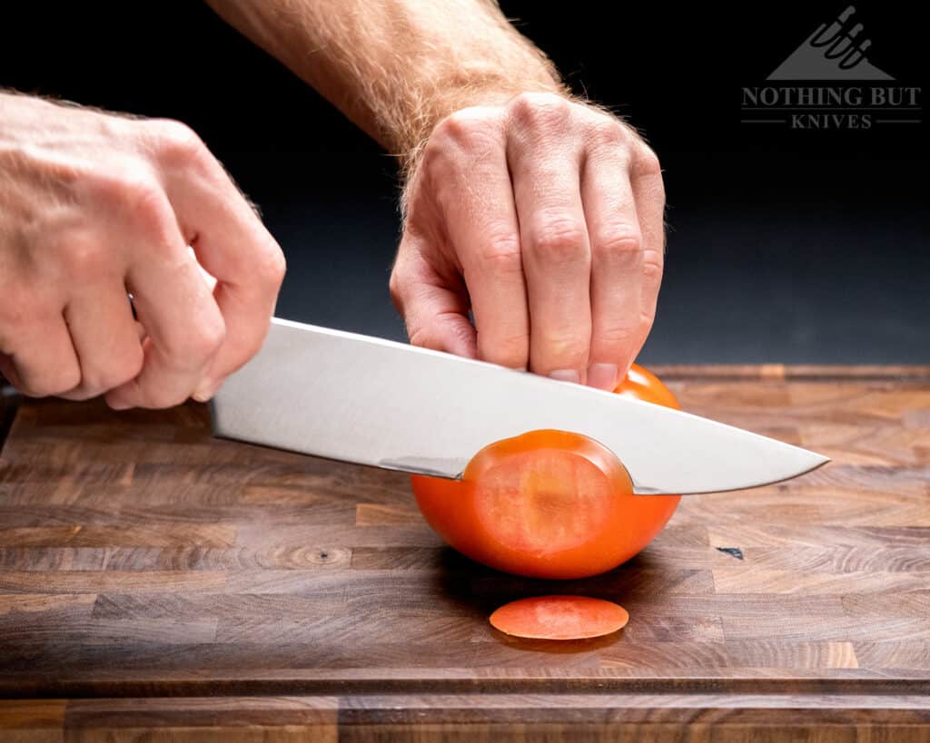 A close-up of the Cangshan TC chef knife cutting through a tomato that illustrates it's slicing ability.