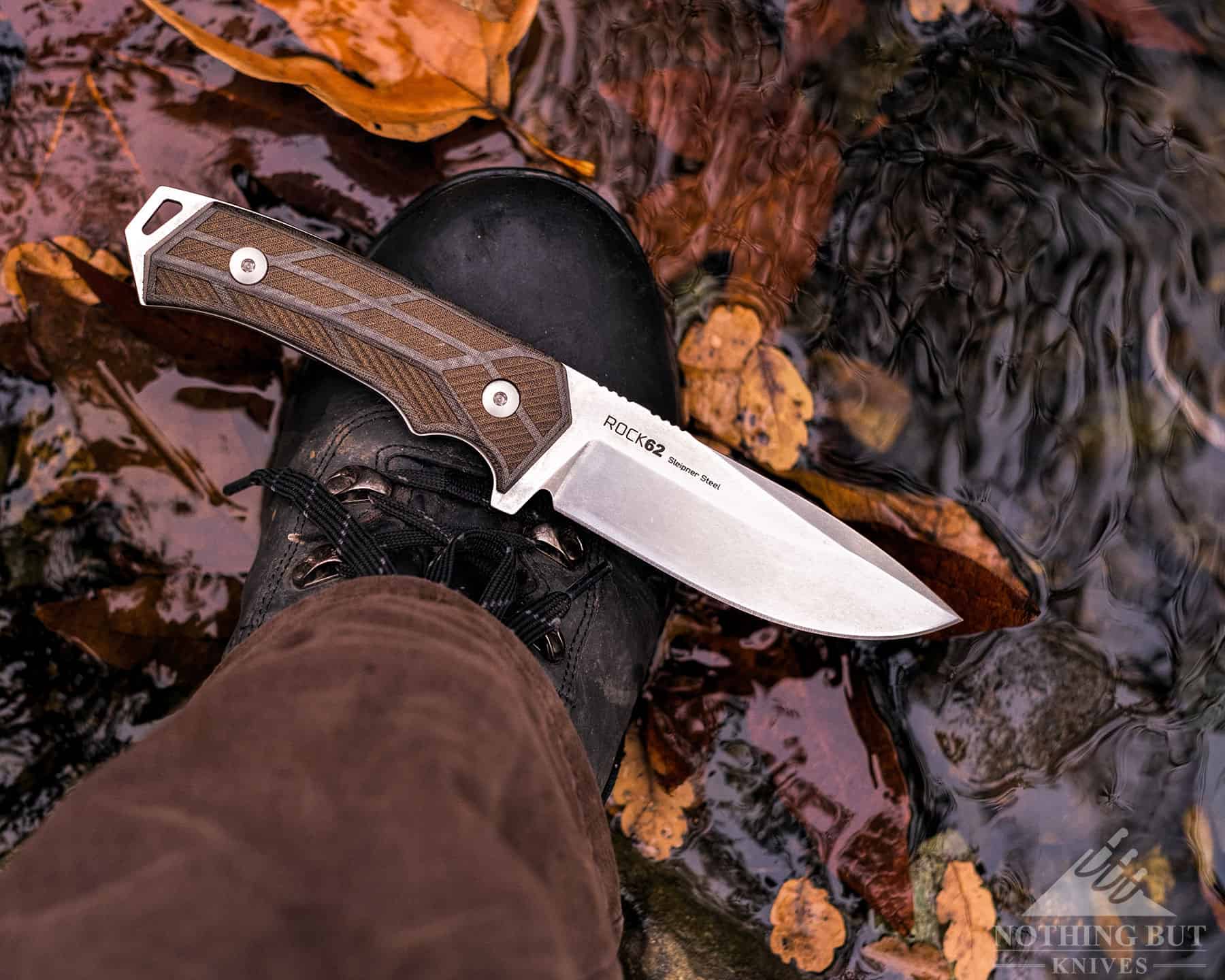 The Woox Rock 62 shown balanced on a hiking boot above a creek.