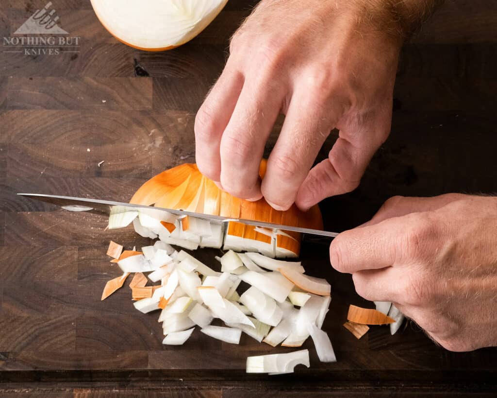 A close-up of a person slicing onions with the Imarku 8 inch Japanese chef knife