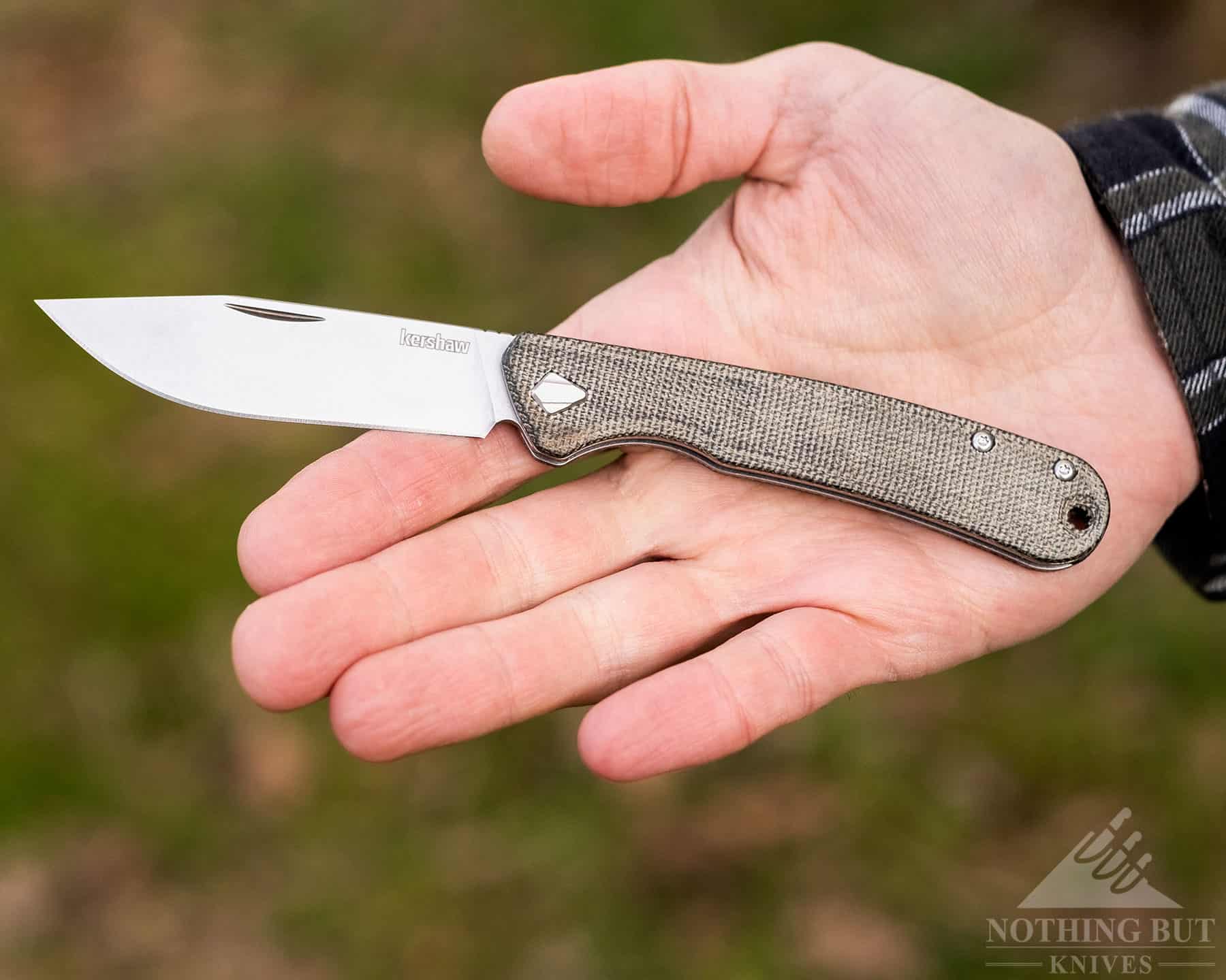 The Kershaw Federalist in the open palm of a person's hand to show scale and the darkening micarta handle. 