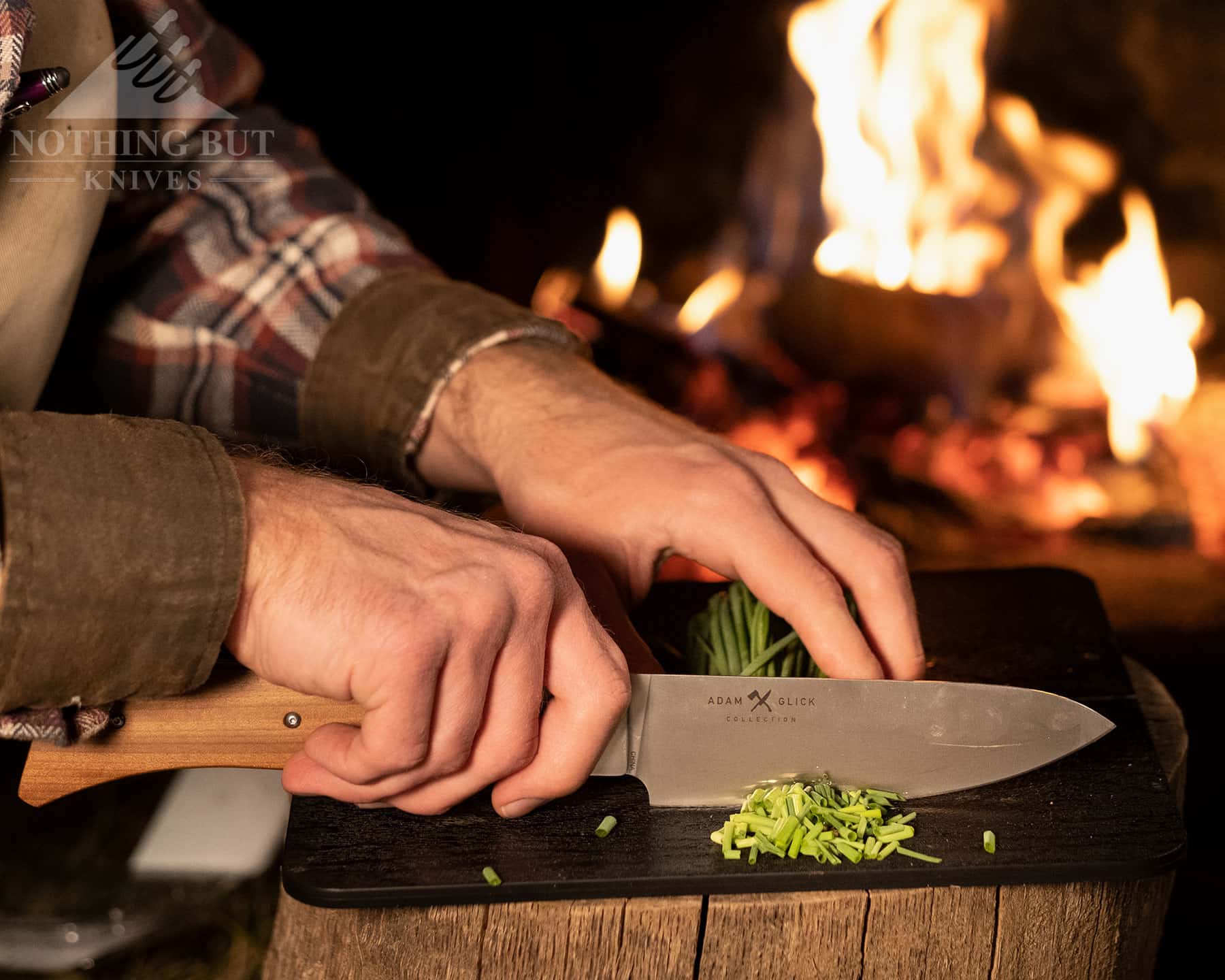 The Messermeister Adventure chef knife chopping green onions on the folding cutting board that is part of the kit.