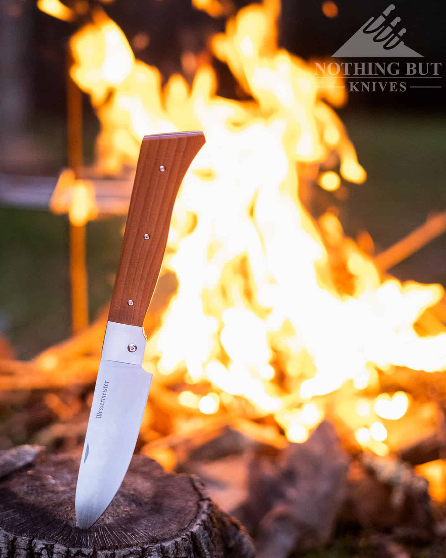 The Messermeister Adventure Chef Knife in the open position next to a campfire.