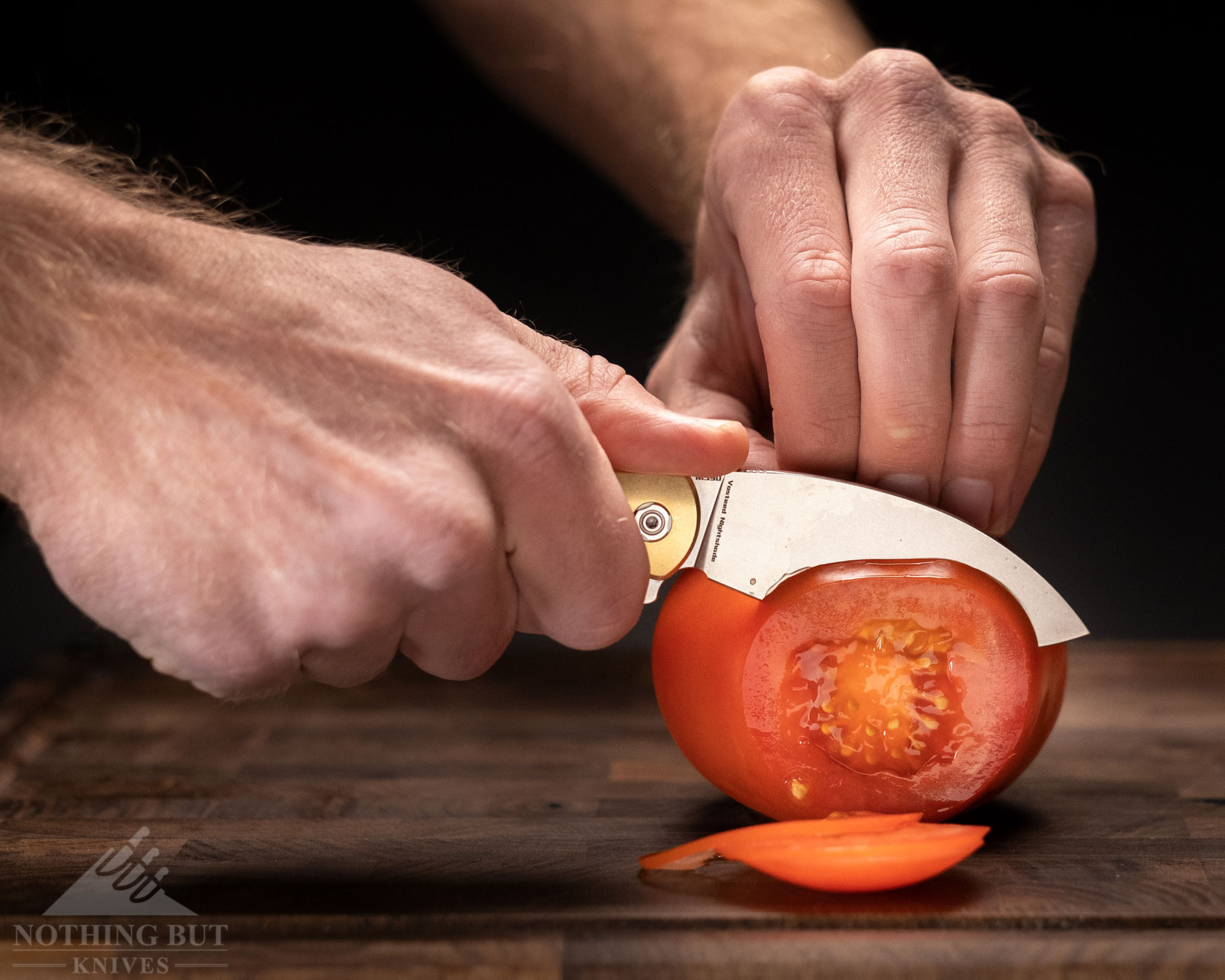 A close-up of the Vosteed Nightshade being used to cut tomato slices. 