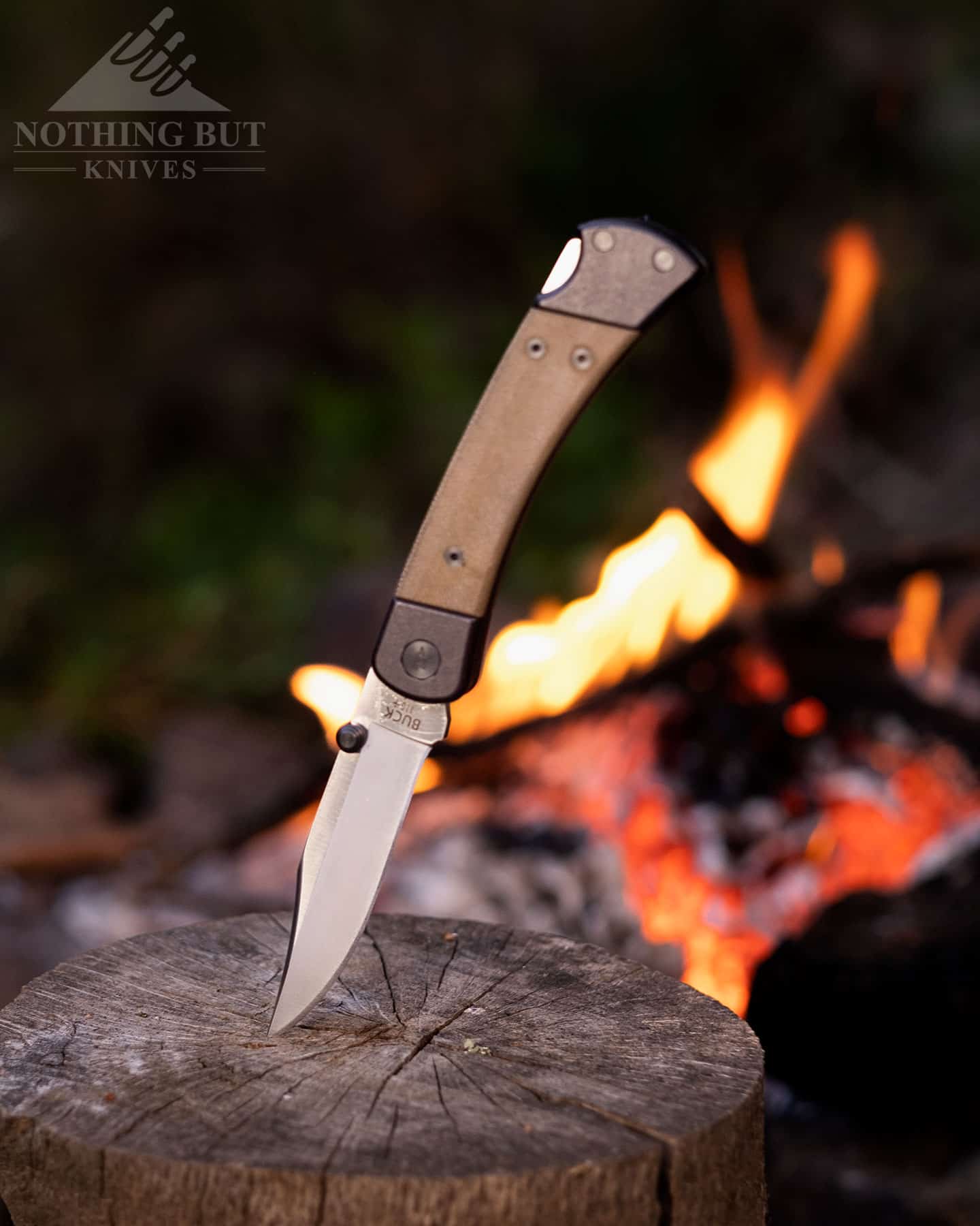 The Buck 110 Hunter Sport by a campfire at night in the woods.